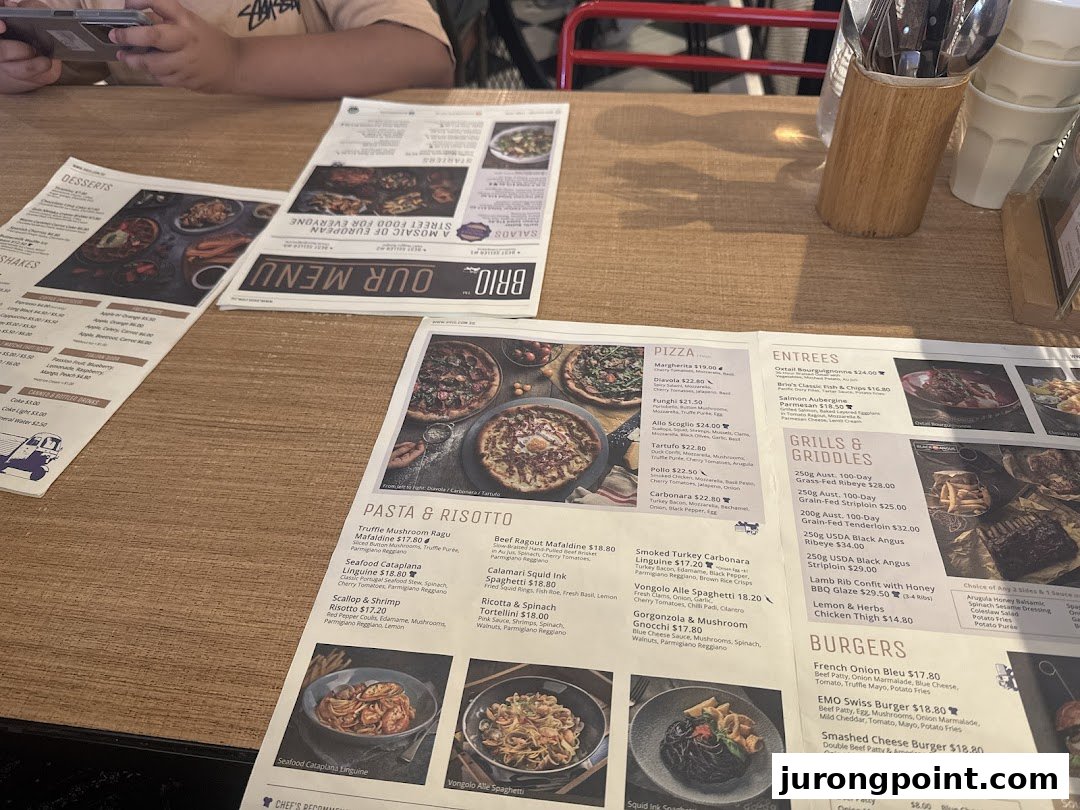 Multiple menus from Brio restaurant displayed on a wooden table, showing various food categories.
