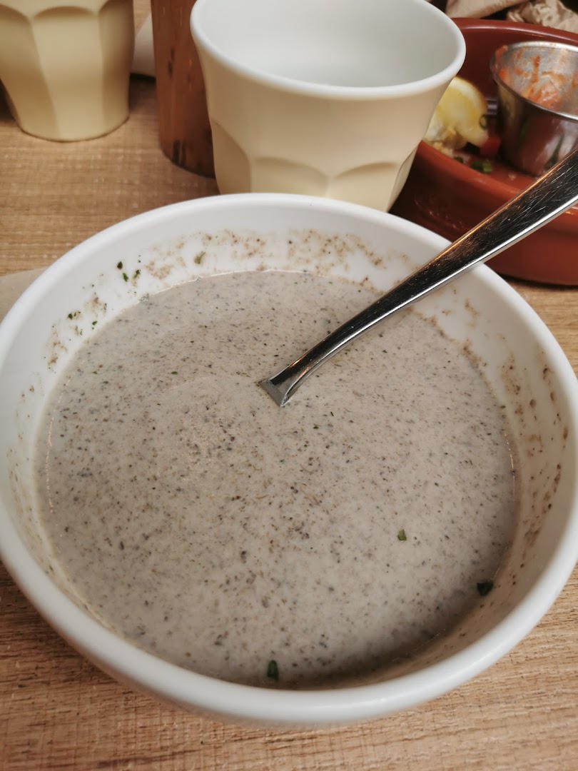 A close-up of a creamy, speckled soup in a white bowl with a spoon, on a wooden table.