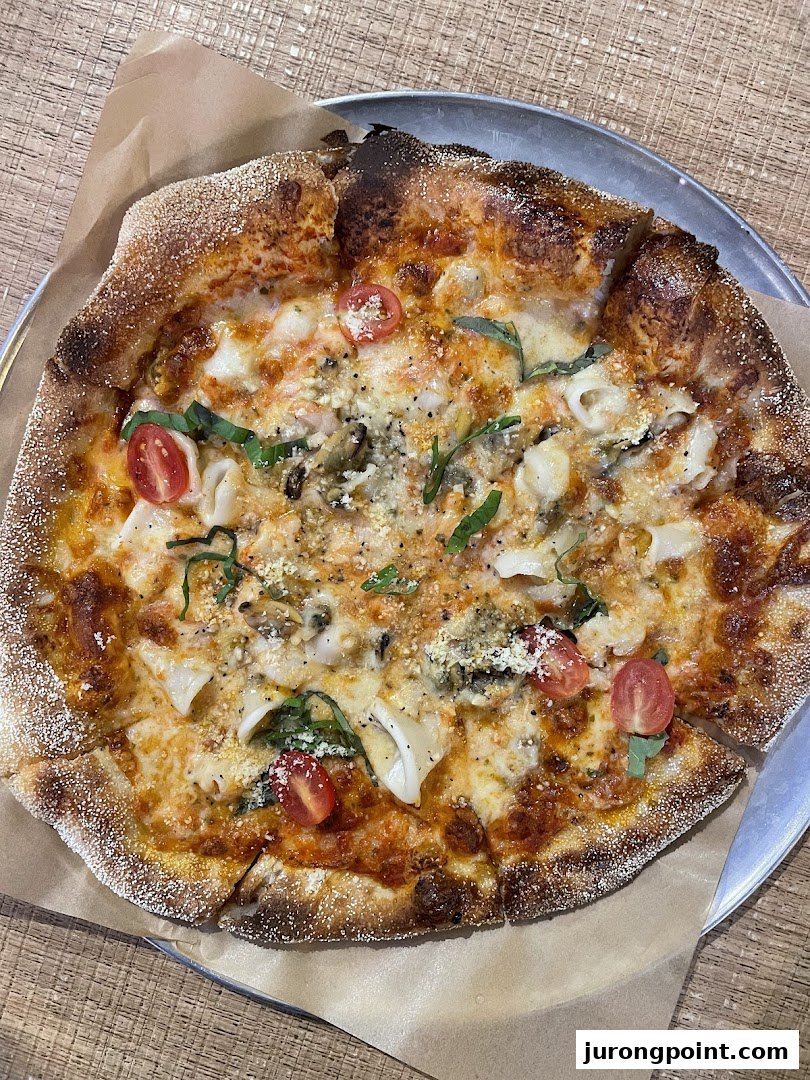 A close-up of a delicious seafood pizza with cherry tomatoes and fresh herbs on a metal tray.