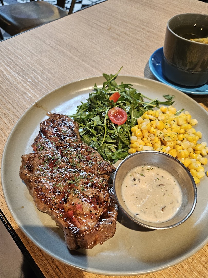 A delicious steak served with fresh greens, corn, and a creamy mushroom sauce.