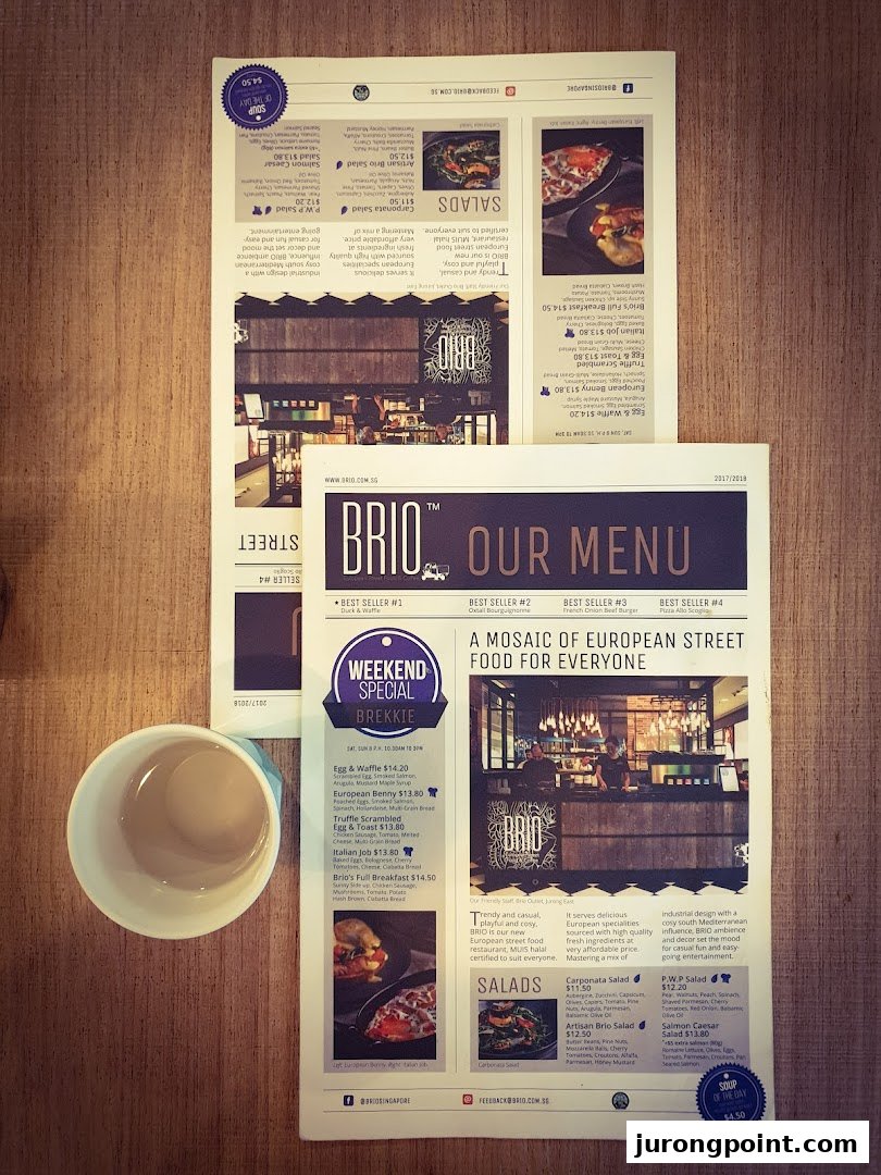 Two Brio restaurant menus and a white cup on a wooden table.