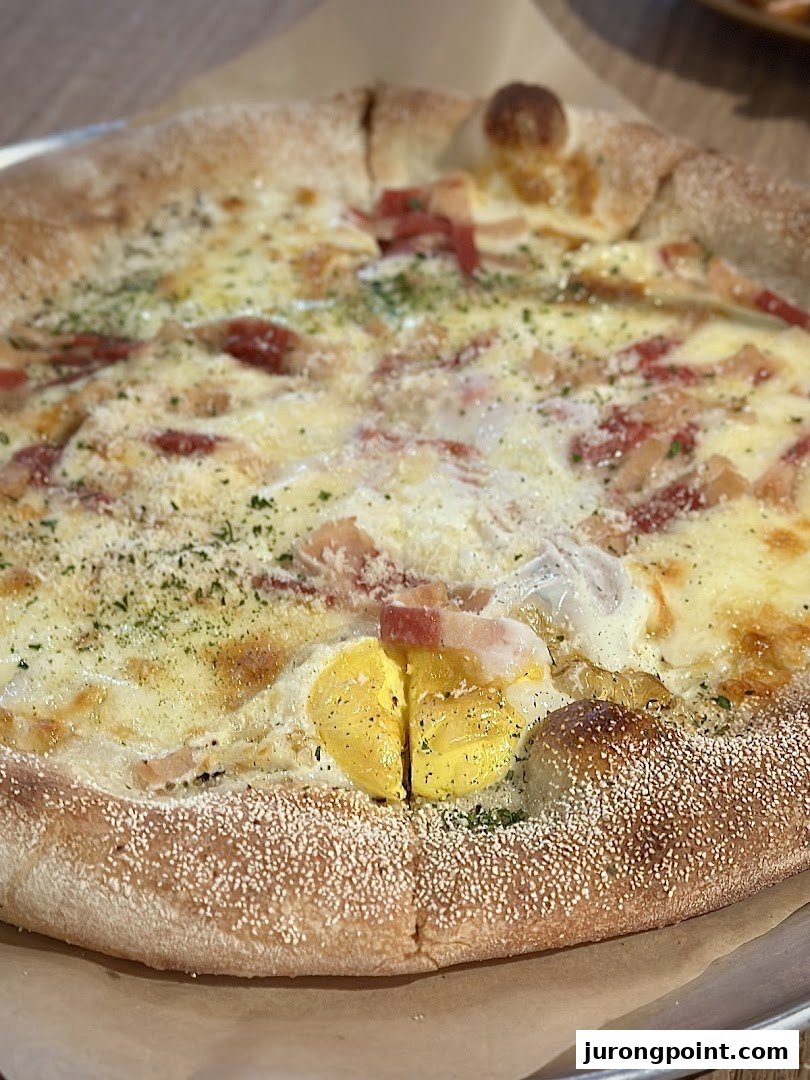 A close-up of a delicious pizza topped with creamy sauce, bacon, herbs, and a perfectly cooked egg yolk.
