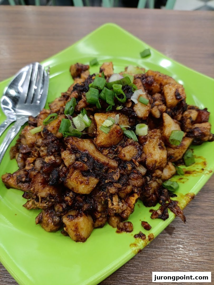 A vibrant green plate holds a delicious serving of stir-fried dark carrot cake, garnished with fresh spring onions.