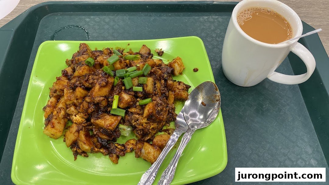 A vibrant plate of fried carrot cake topped with spring onions, served with a mug of milk tea.