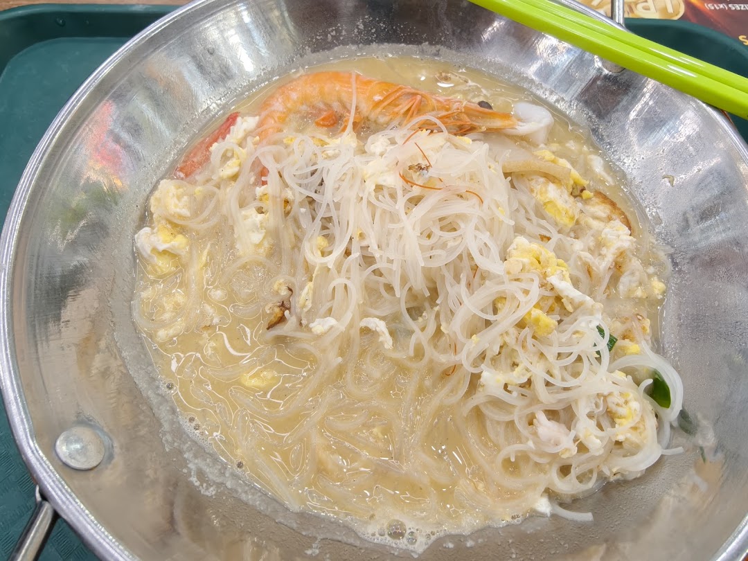 A close-up of a delicious bowl of rice vermicelli noodles with shrimp and scrambled egg in broth.