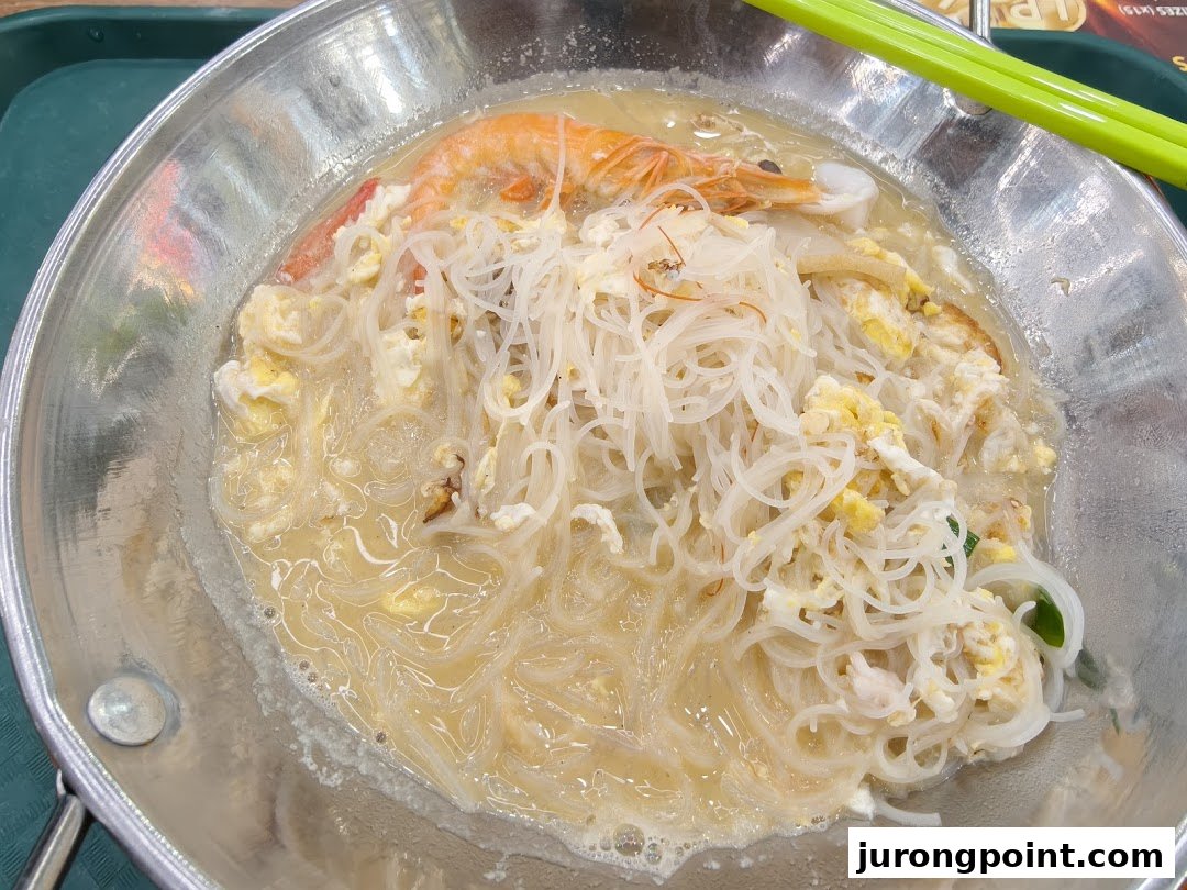 A close-up of a delicious bowl of rice vermicelli noodles with shrimp and scrambled egg in broth.