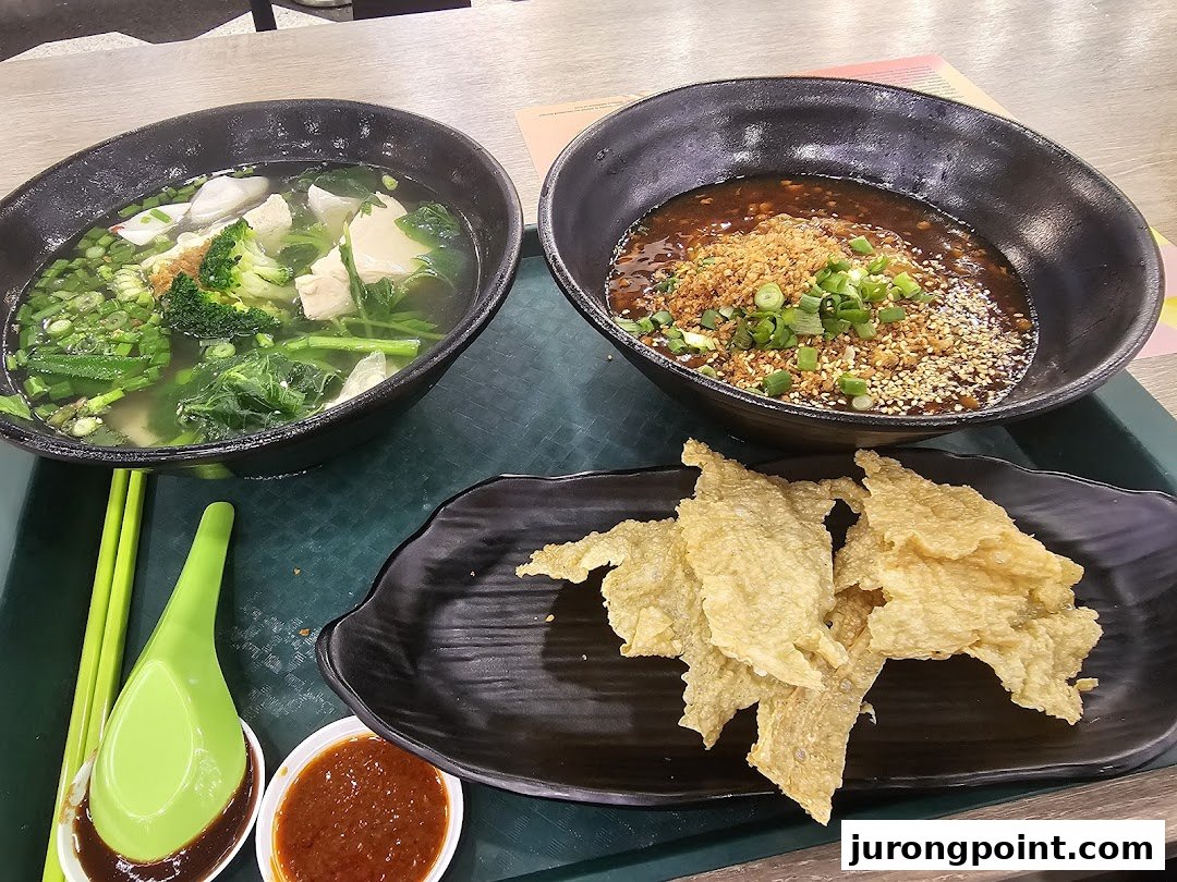 Two delicious Asian noodle/soup bowls with crispy fried wonton skins and dipping sauces on a tray.