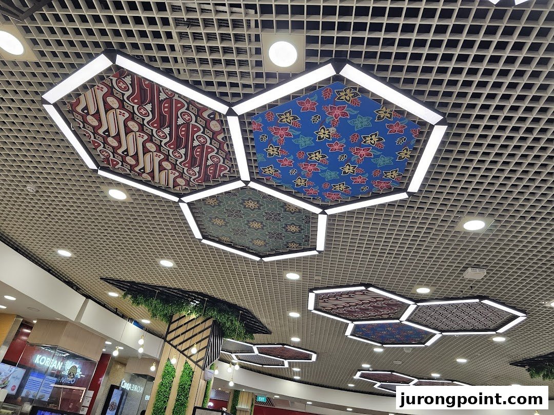 Decorative hexagonal ceiling lights with traditional patterns illuminate a modern food court area.