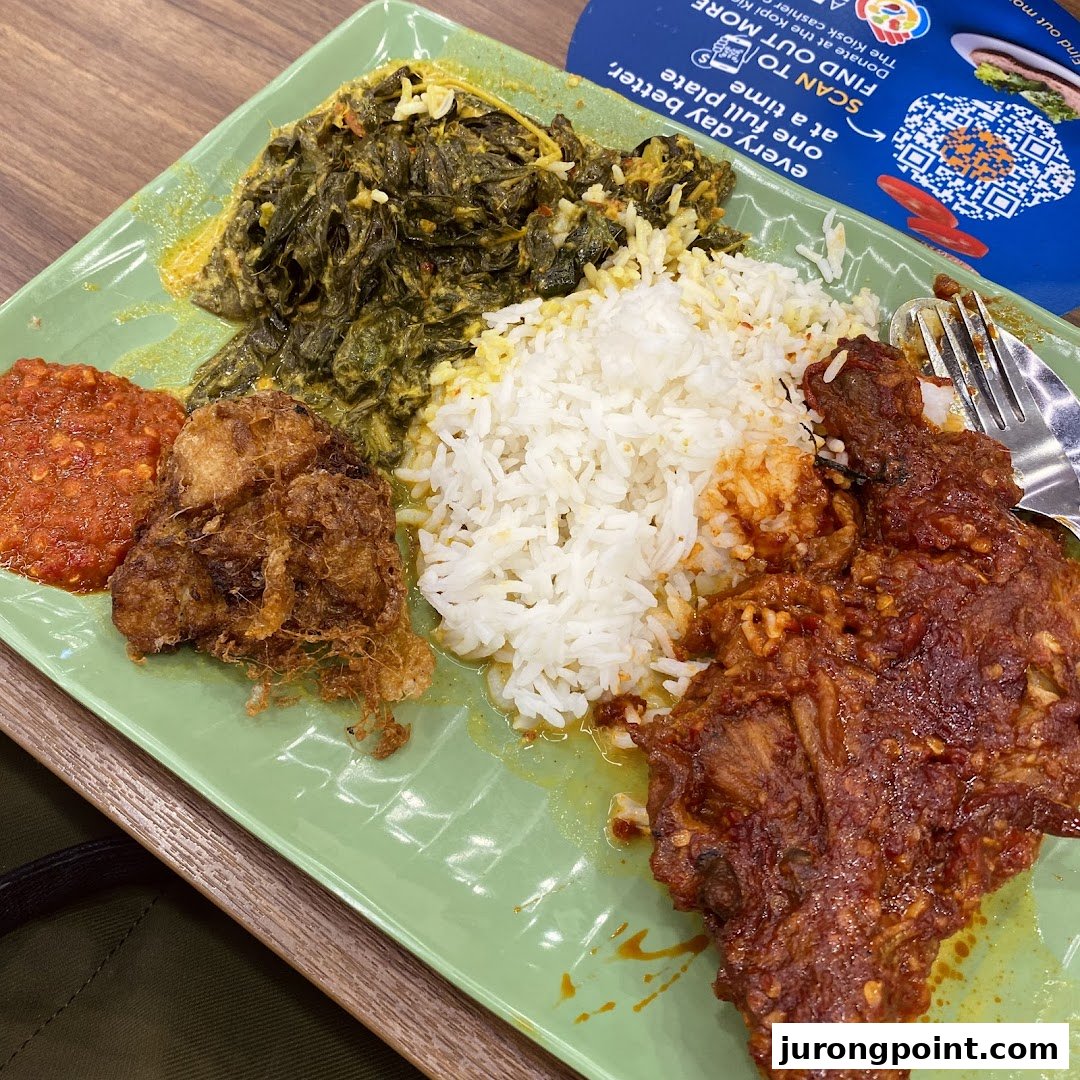 A vibrant plate of Nasi Padang featuring rice, spicy chicken, fried egg, greens, and sambal.