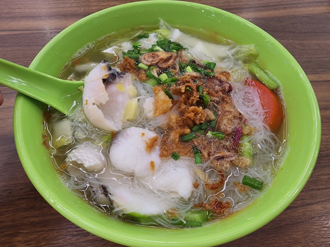 A vibrant bowl of fish bee hoon soup with tender fish slices, fried shallots, and vegetables.