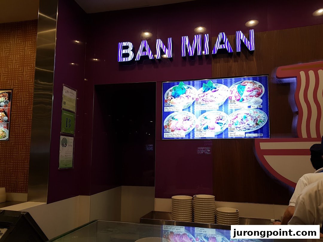A digital menu display at a food stall featuring various Ban Mian and Mee Hoon Kuay dishes.