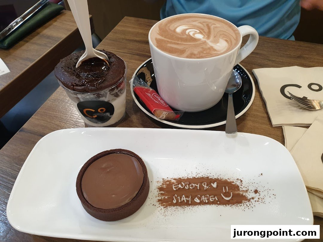 A chocolate lava cake, chocolate tart, and hot chocolate served on a wooden table at Chocolate Origin.