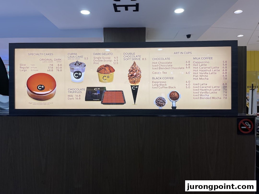A brightly lit menu board displaying cakes, gelato, truffles, and various chocolate and coffee beverages.