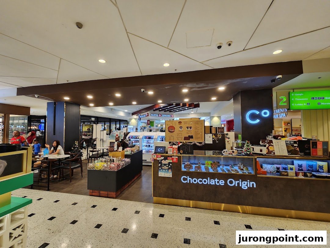 Chocolate Origin shop in a mall, featuring its counter, display cases, and a cozy seating area.