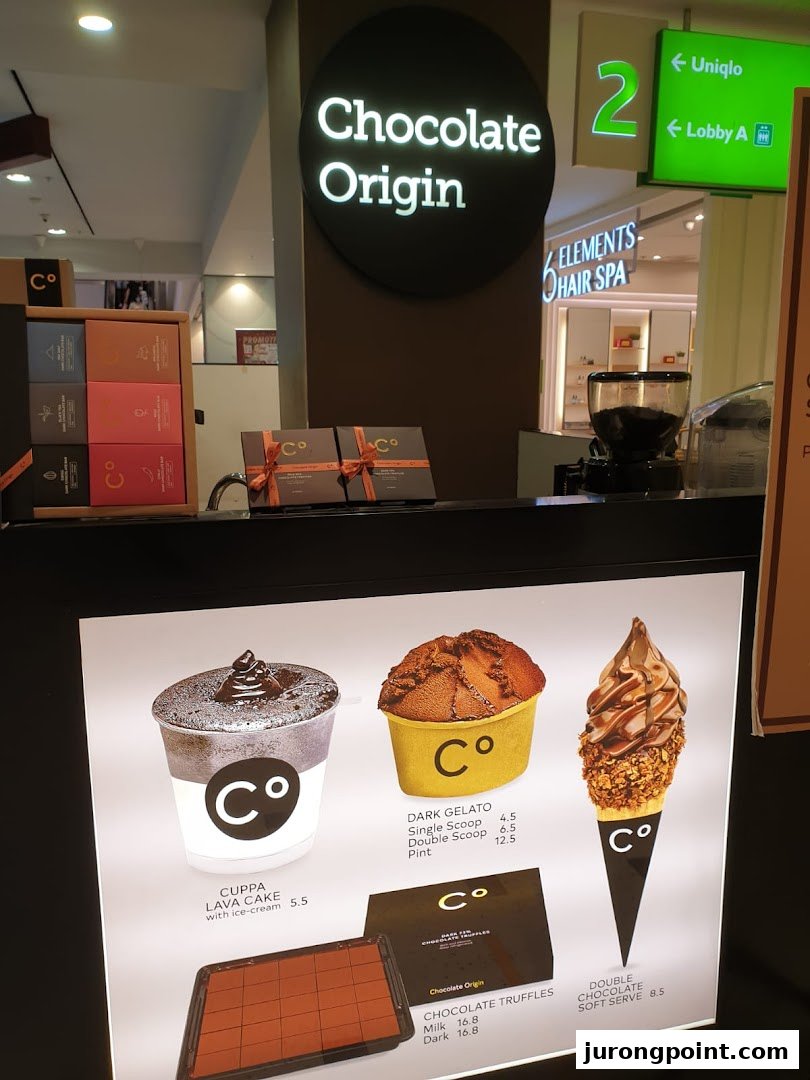 A Chocolate Origin counter displaying various chocolate desserts and a menu board with prices.