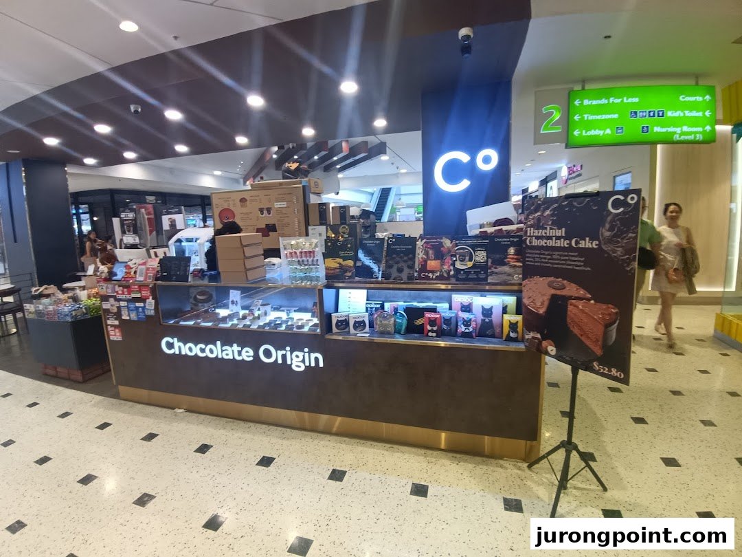 A Chocolate Origin kiosk showcasing delicious cakes, chocolates, and a Hazelnut Chocolate Cake promotion.