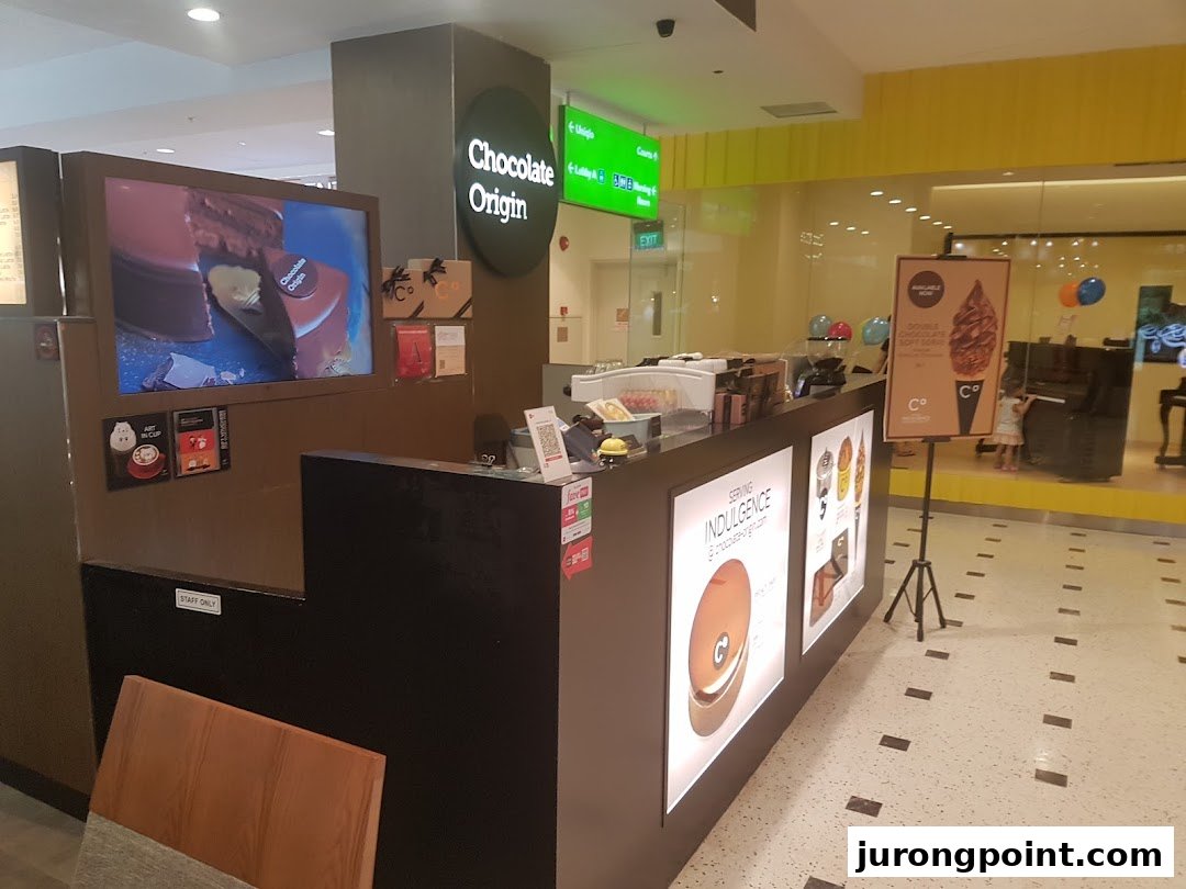The Chocolate Origin counter features a digital display, product advertisements, and a soft-serve ice cream standee.