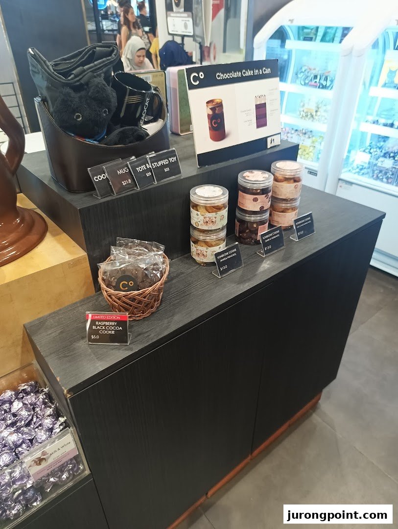 An interior shot of Chocolate Origin showcasing various merchandise, packaged cookies, and a 'Chocolate Cake in a Can' display.
