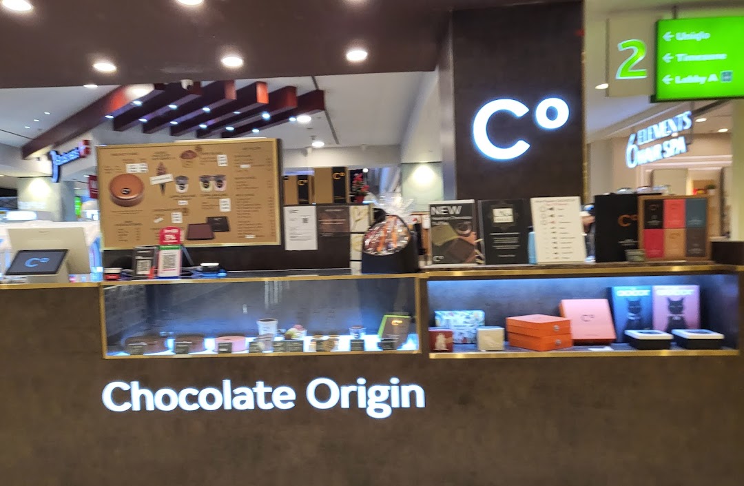 A counter view of Chocolate Origin showcasing cakes, chocolates, and a menu board.