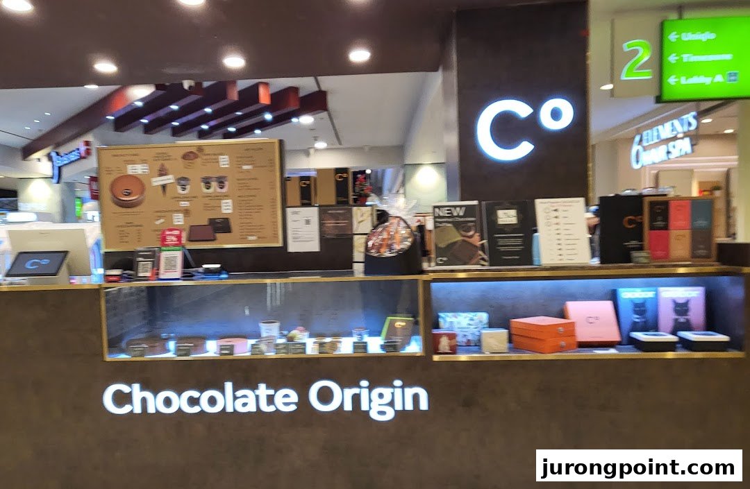 A counter view of Chocolate Origin showcasing cakes, chocolates, and a menu board.