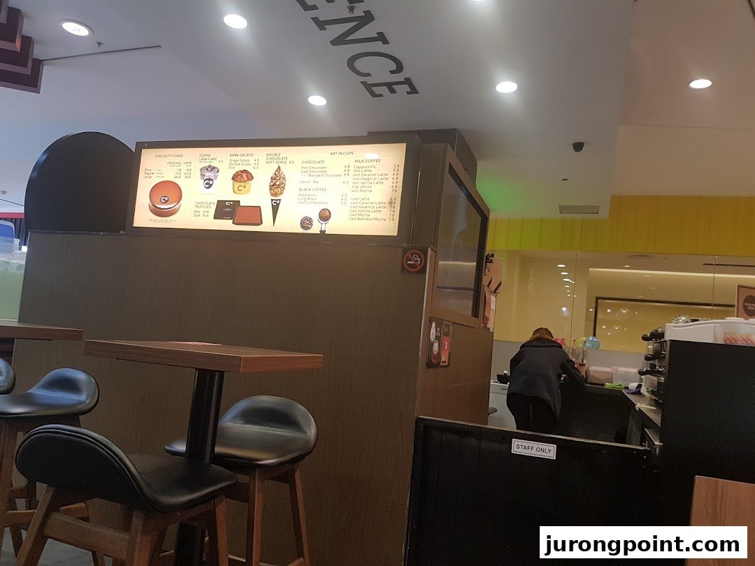 Interior view of Chocolate Origin featuring a detailed menu board, seating area, and staff.