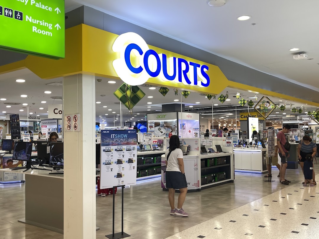 Interior view of COURTS electronics store, showcasing various tech products and customers browsing.