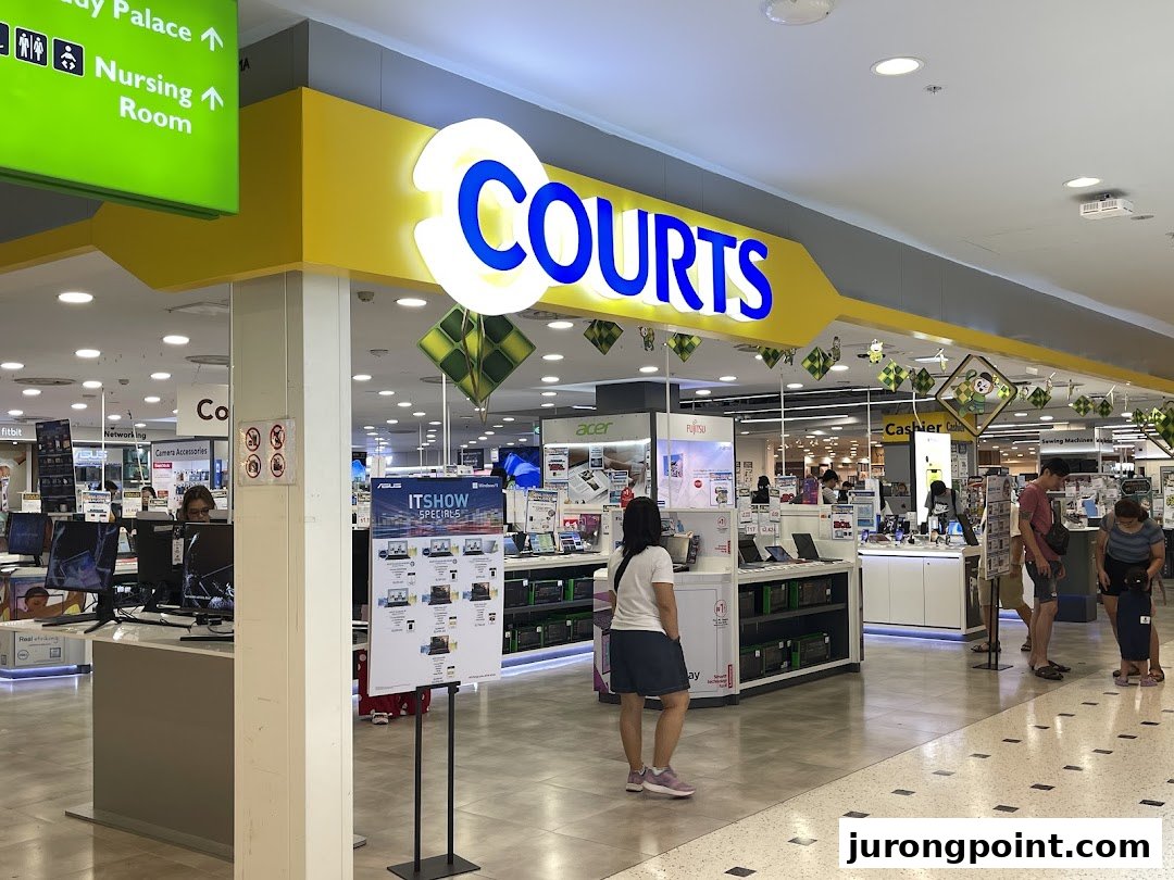Interior view of COURTS electronics store, showcasing various tech products and customers browsing.