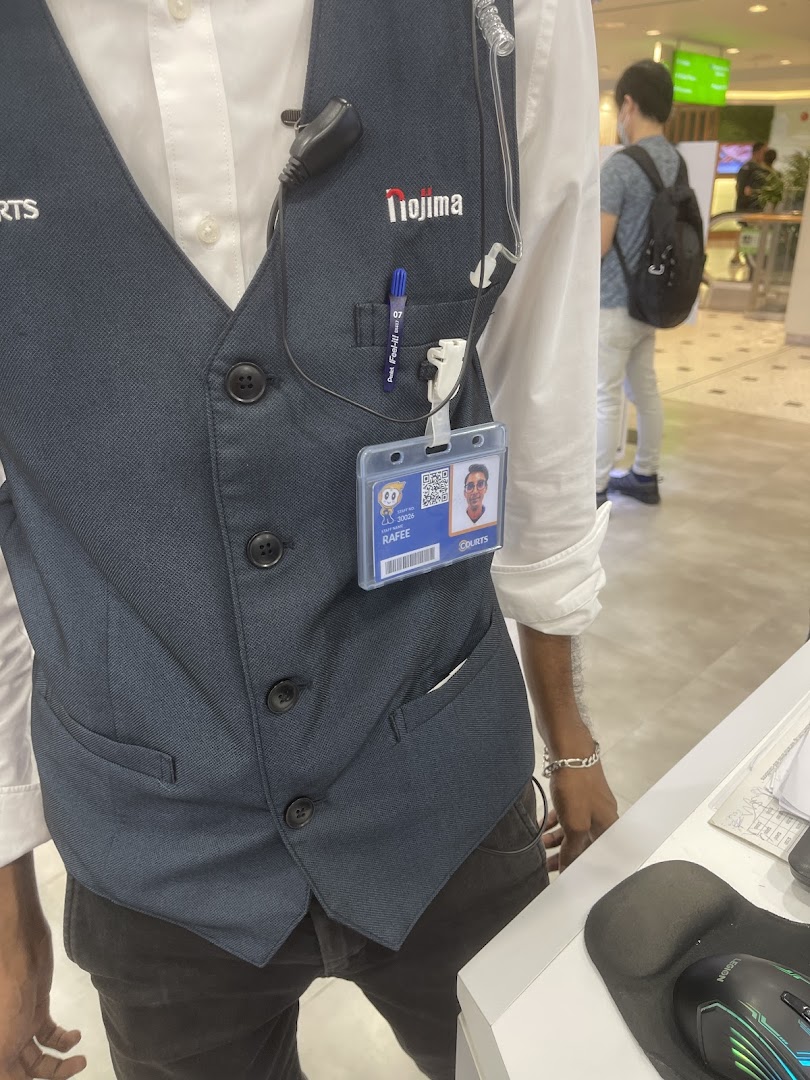 A close-up of a COURTS staff member wearing a vest and ID badge in the store.