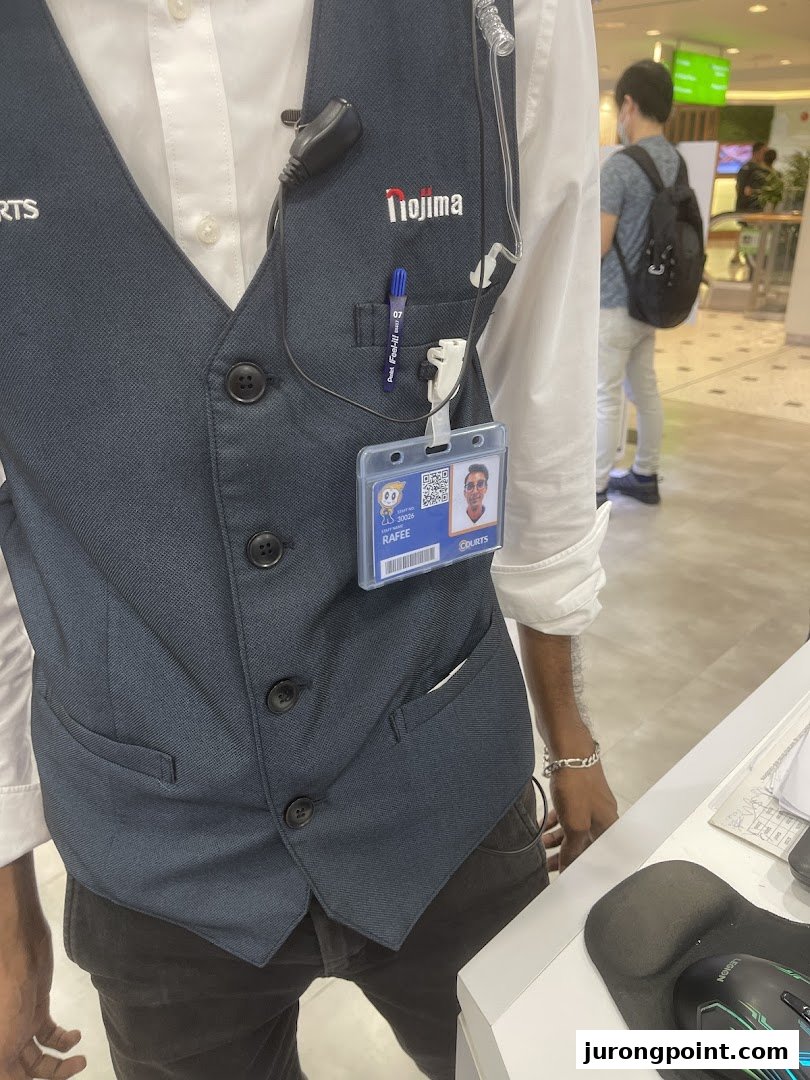 A close-up of a COURTS staff member wearing a vest and ID badge in the store.