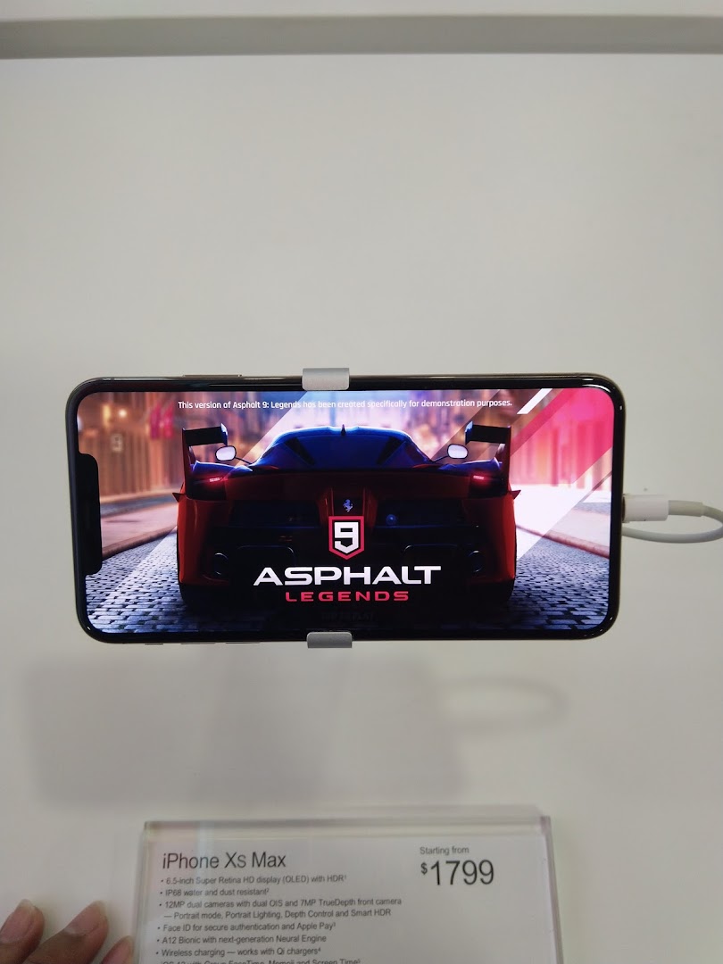 An iPhone Xs Max on display at COURTS, showcasing 'Asphalt Legends' with its price and features.