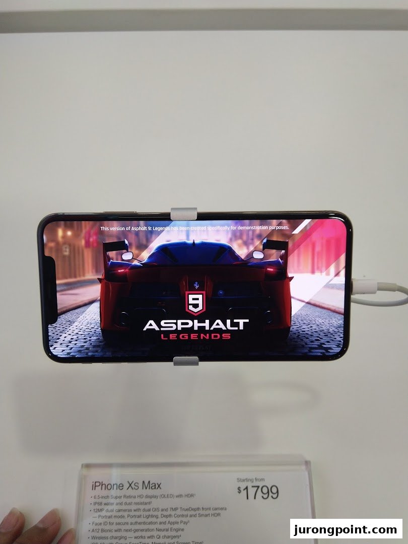An iPhone Xs Max on display at COURTS, showcasing 'Asphalt Legends' with its price and features.