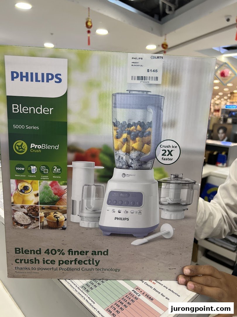 A person holds a Philips blender box with a Courts price tag in a retail store.