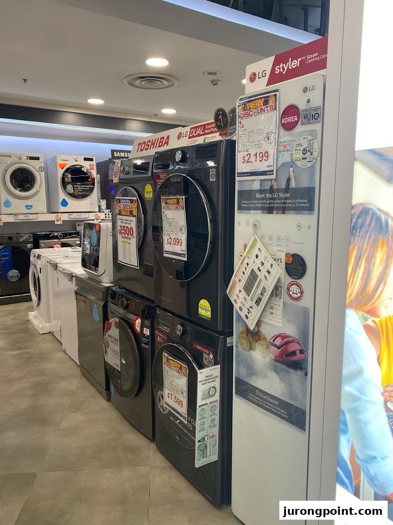 An electronics store aisle showcasing various washing machines and an LG Styler appliance.