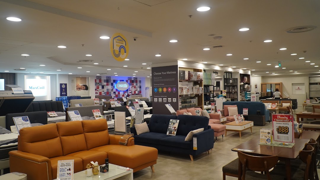An expansive interior view of COURTS showcasing a wide selection of furniture, including sofas, mattresses, and dining sets.