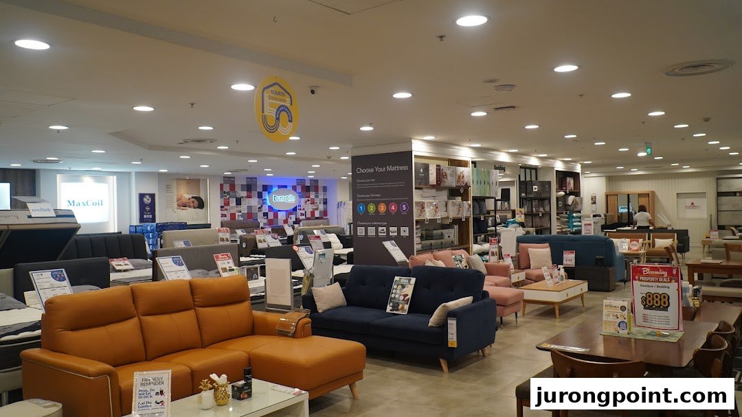An expansive interior view of COURTS showcasing a wide selection of furniture, including sofas, mattresses, and dining sets.