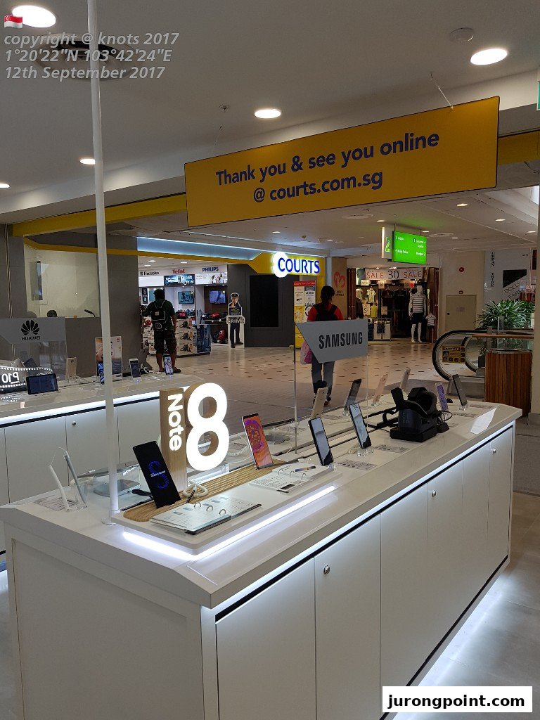 An in-store display of Samsung Note 8 phones at COURTS, featuring a prominent online presence sign.