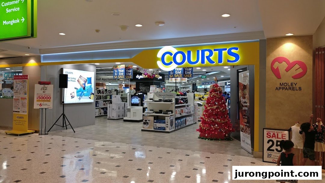 The brightly lit entrance of COURTS electronics store, featuring a festive Christmas tree and sale promotions.