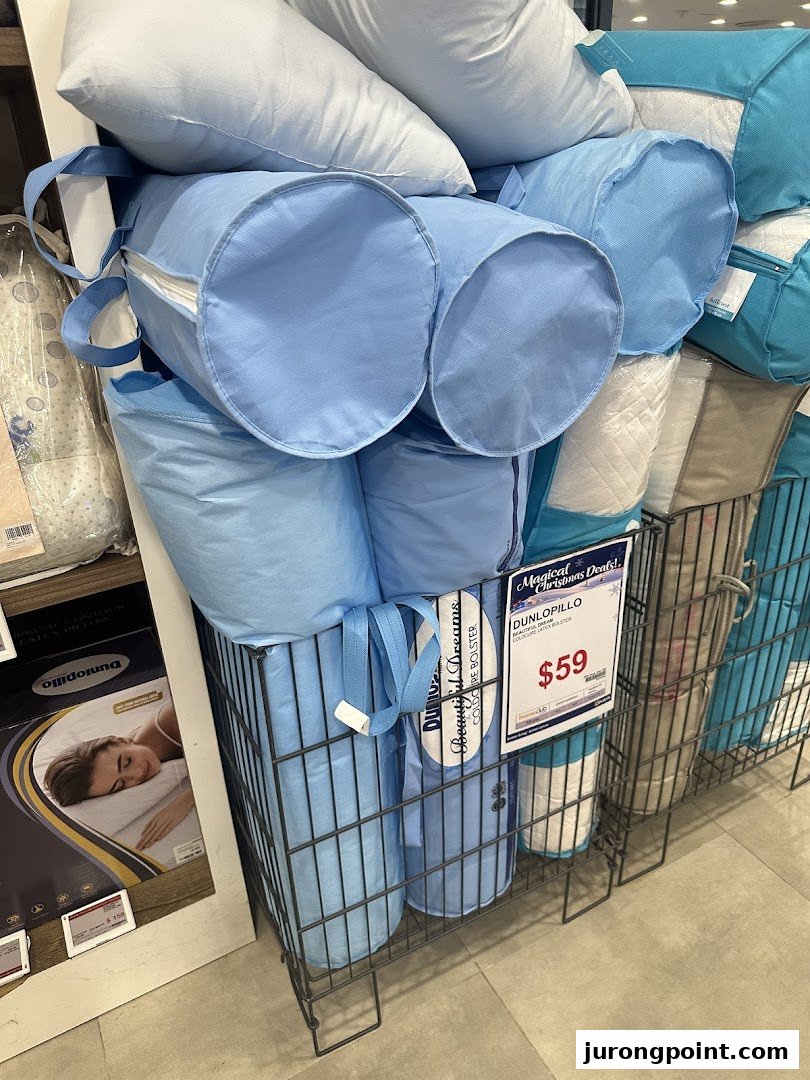 A retail display of pillows and bolsters, including light blue packaged items, in wire bins at COURTS.