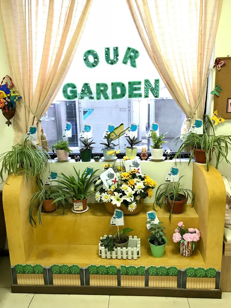 An indoor garden display with various potted plants and flowers on a tiered stand, featuring a 'OUR GARDEN' sign.
