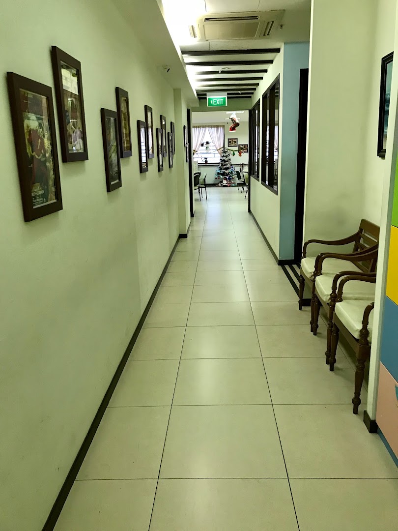 A long, well-lit hallway adorned with framed pictures, leading to a festive room with a Christmas tree.