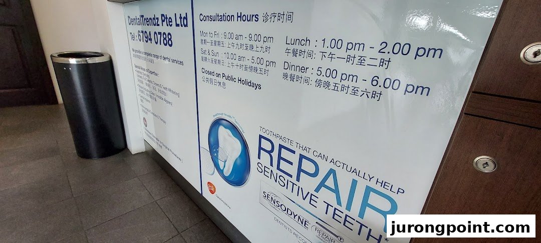A sign displaying DentalTrendz's consultation hours, contact information, and a Sensodyne advertisement.
