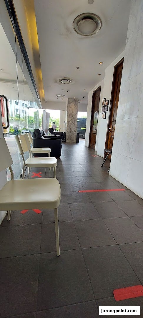 A bright, spacious waiting area with chairs and a sofa, featuring social distancing markers on the floor.