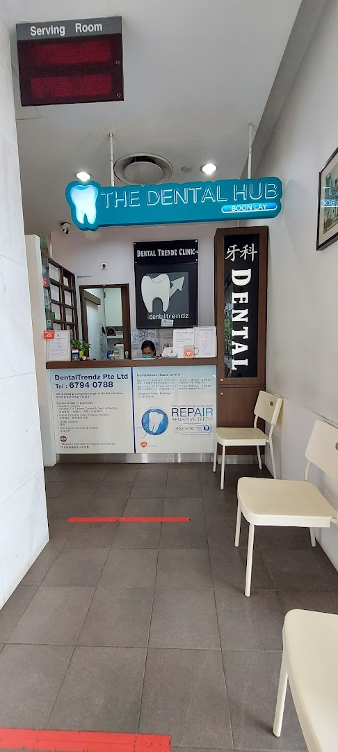 Interior view of DentalTrendz Boon Lay reception area with a staff member and waiting chairs.