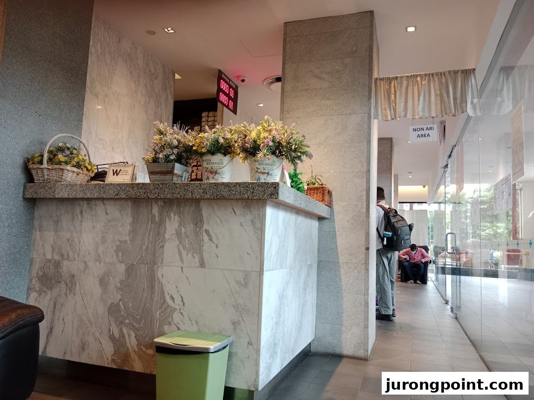 A well-lit reception area featuring a marble-patterned desk adorned with floral arrangements.