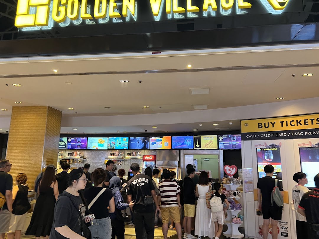 A bustling mall entrance area featuring a cinema facade, ticket kiosks, and people queuing.