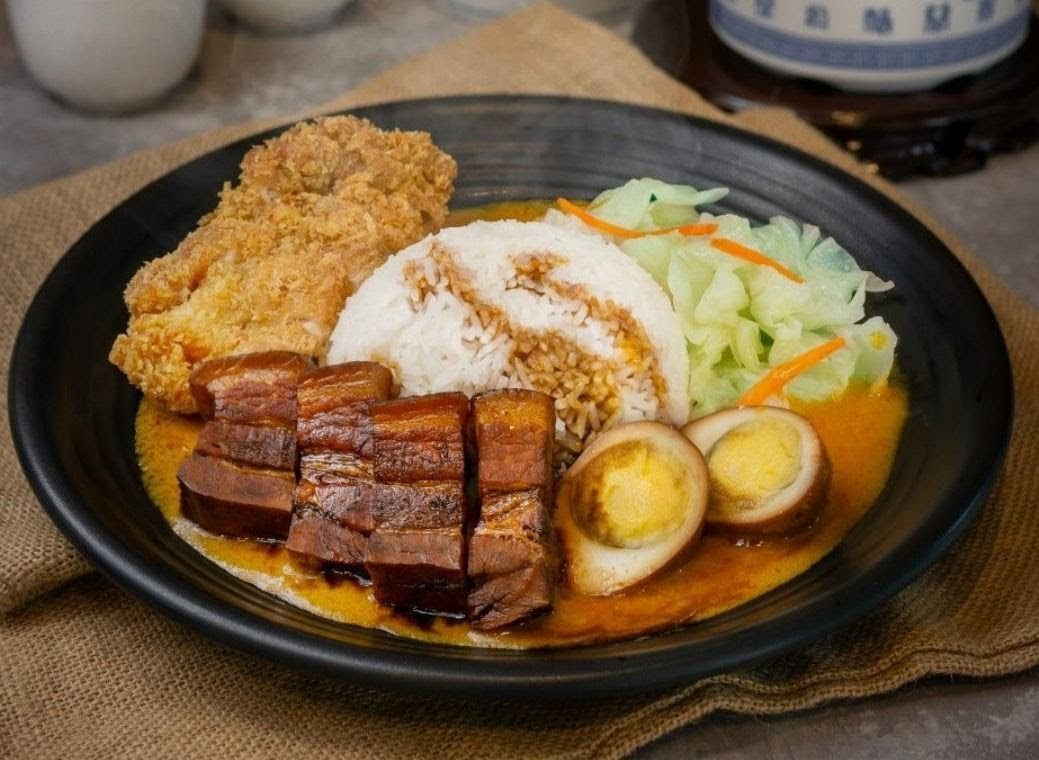 A delicious plate featuring rice, braised pork belly, fried chicken, braised eggs, and fresh cabbage.
