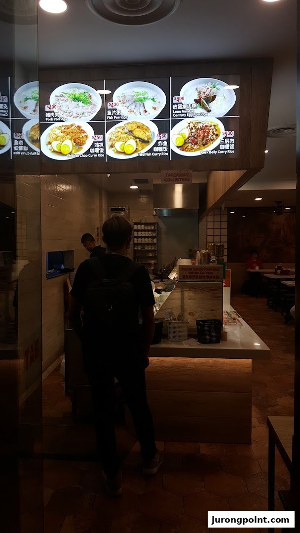 A customer stands at the counter of 'EAT.' with a digital menu board displaying various Asian dishes.