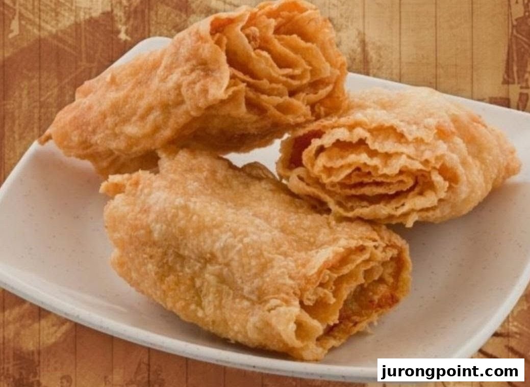 Three golden-brown fried pastries or rolls are presented on a white rectangular plate.