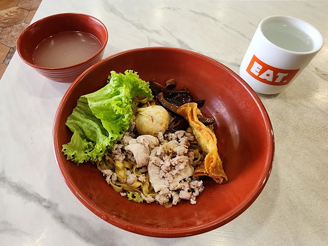 A vibrant bowl of noodles with minced meat, vegetables, and a fried wonton, served with soup and water.