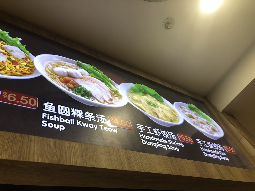 A brightly lit menu board displaying various noodle and dumpling soup dishes with their prices.